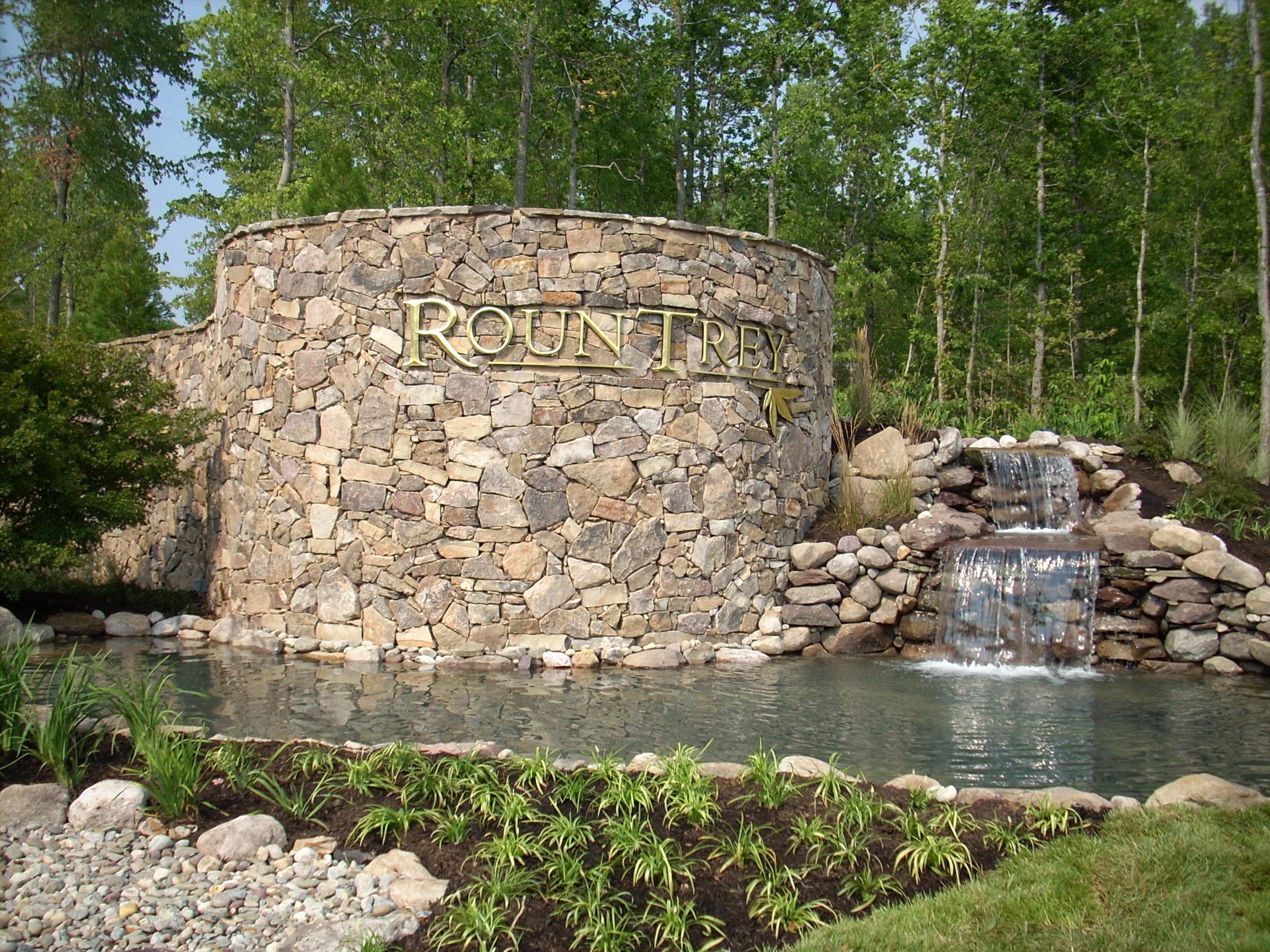 The stone Rountrey entrance sign with a waterfall