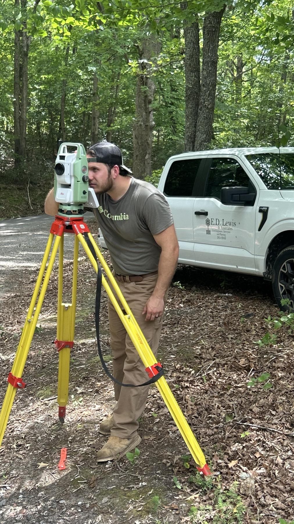 An E.D. Lewis surveyor setting up a total station beside a company truck
