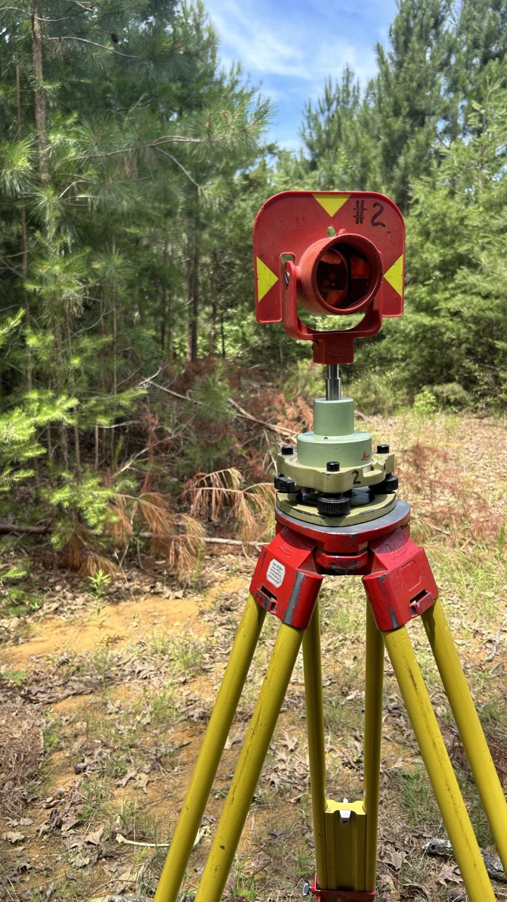 A survey prism on a tripod over a point on a cleared site