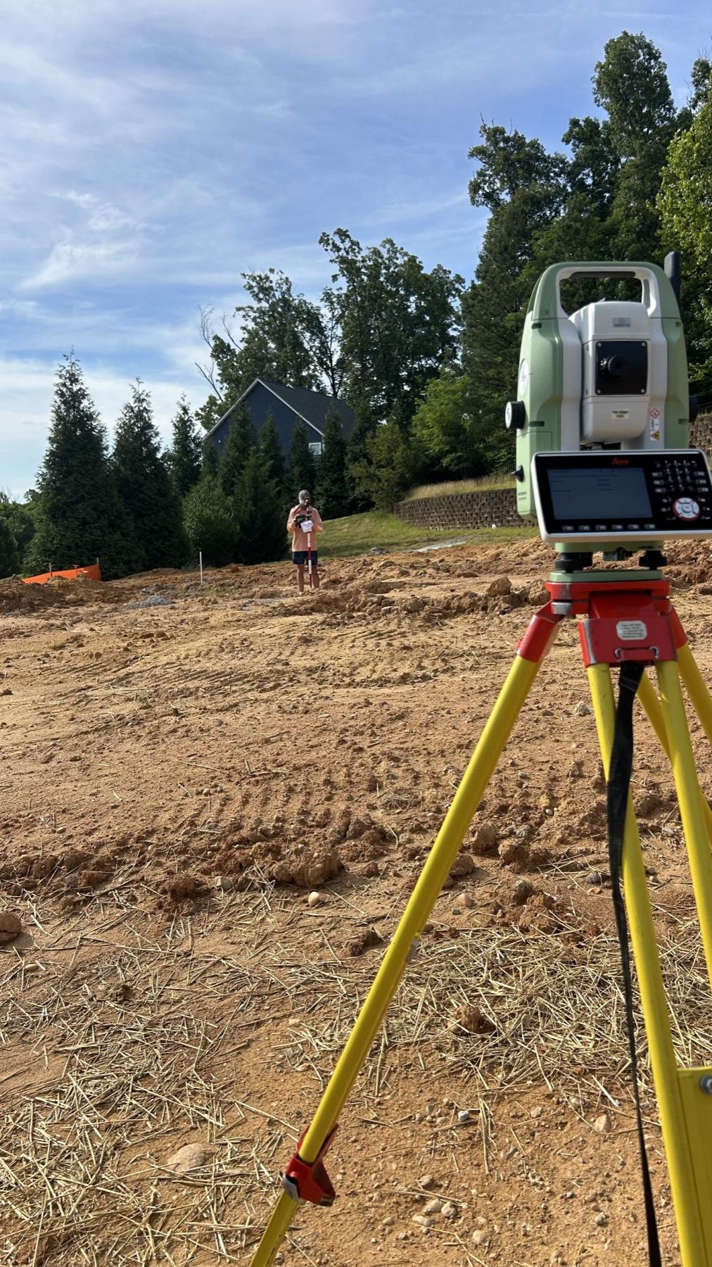 A total station on a tripod on a graded lot