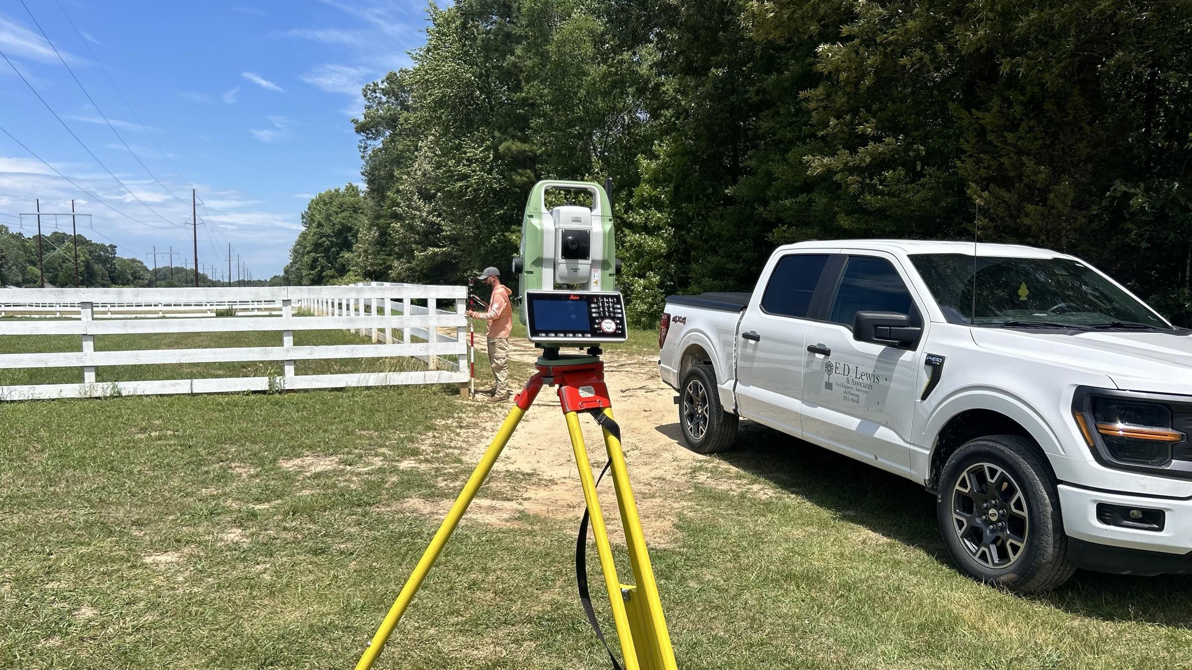 An E.D. Lewis total station set up in a field beside a company truck