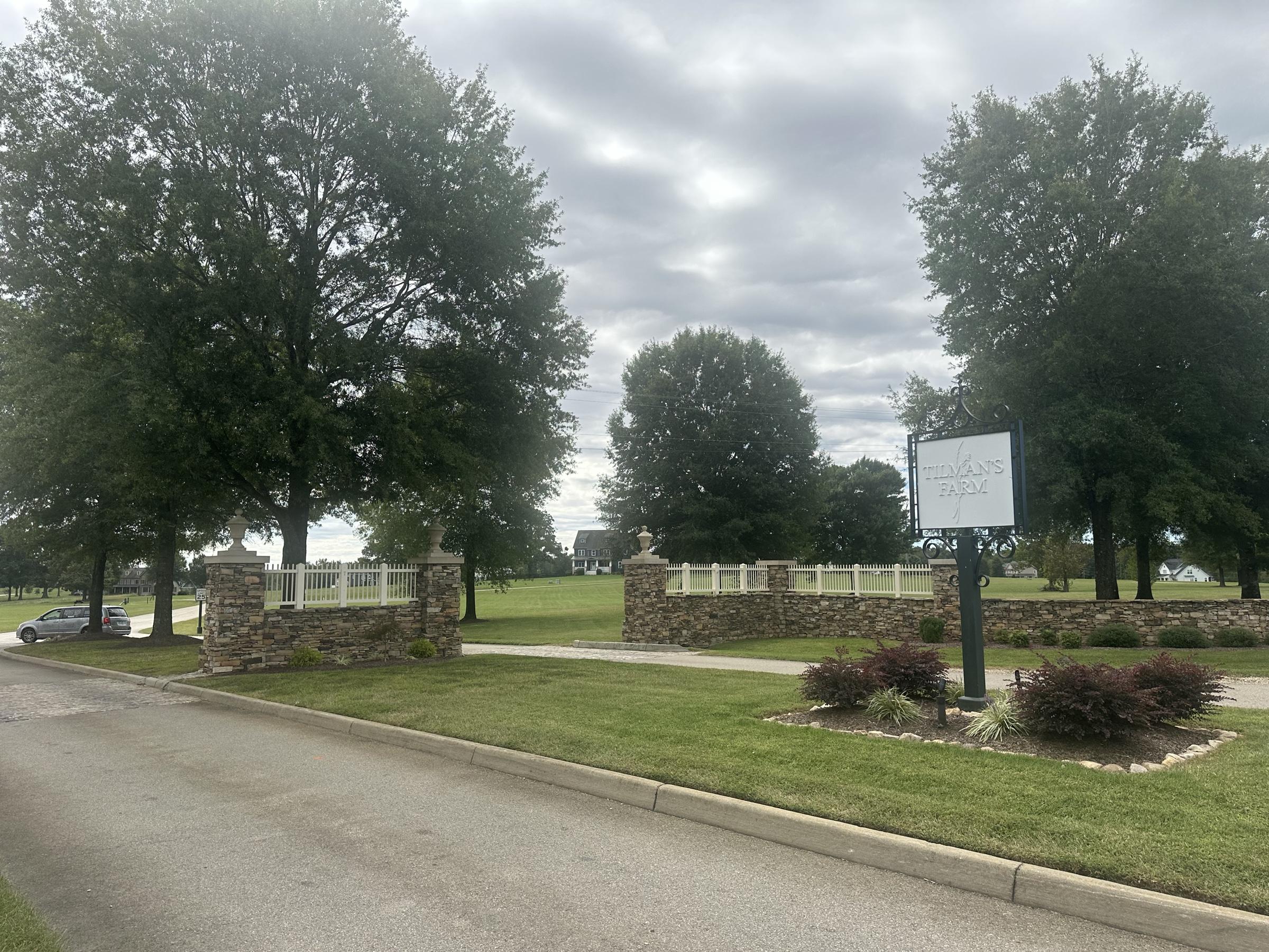 The Tilman Farms entrance sign, stone piers and white fencing